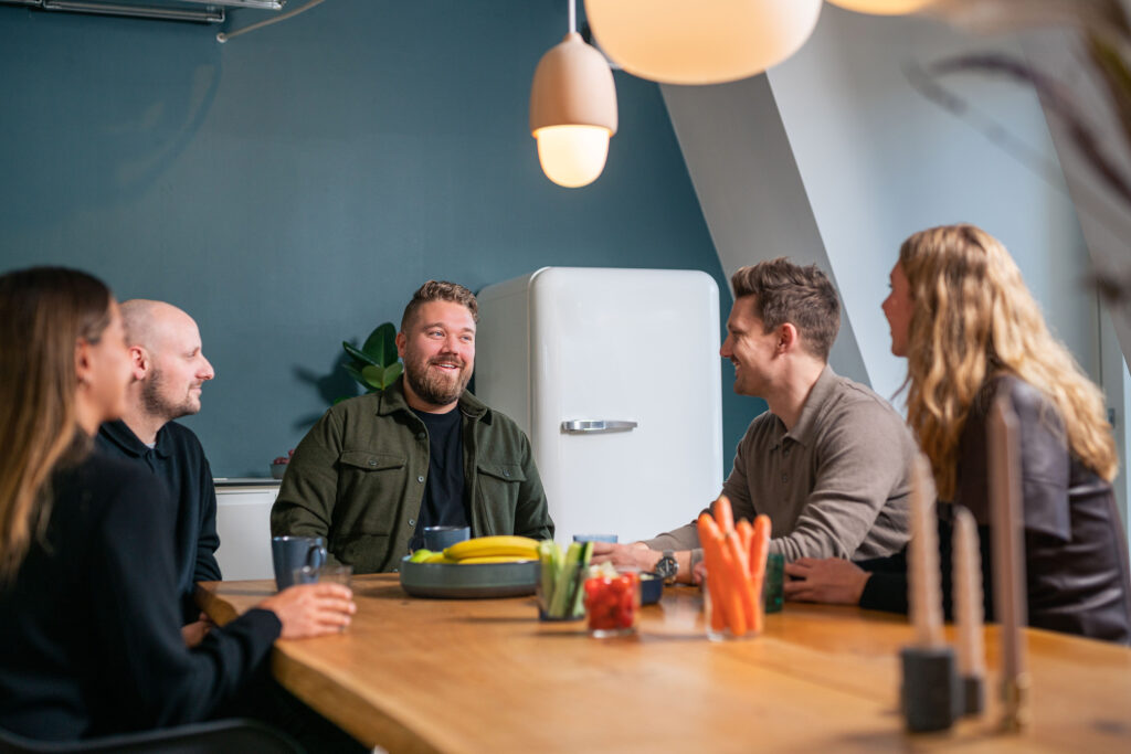 Glade ansatte fra Searchmind der sidder og spiser snacks